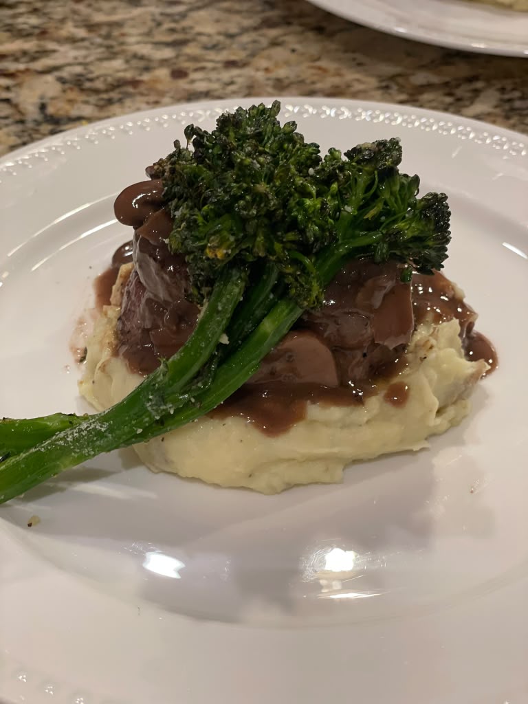 Plated filet with mashed potatoes, broccolini and red wine jus, prepared by Seasoned Table