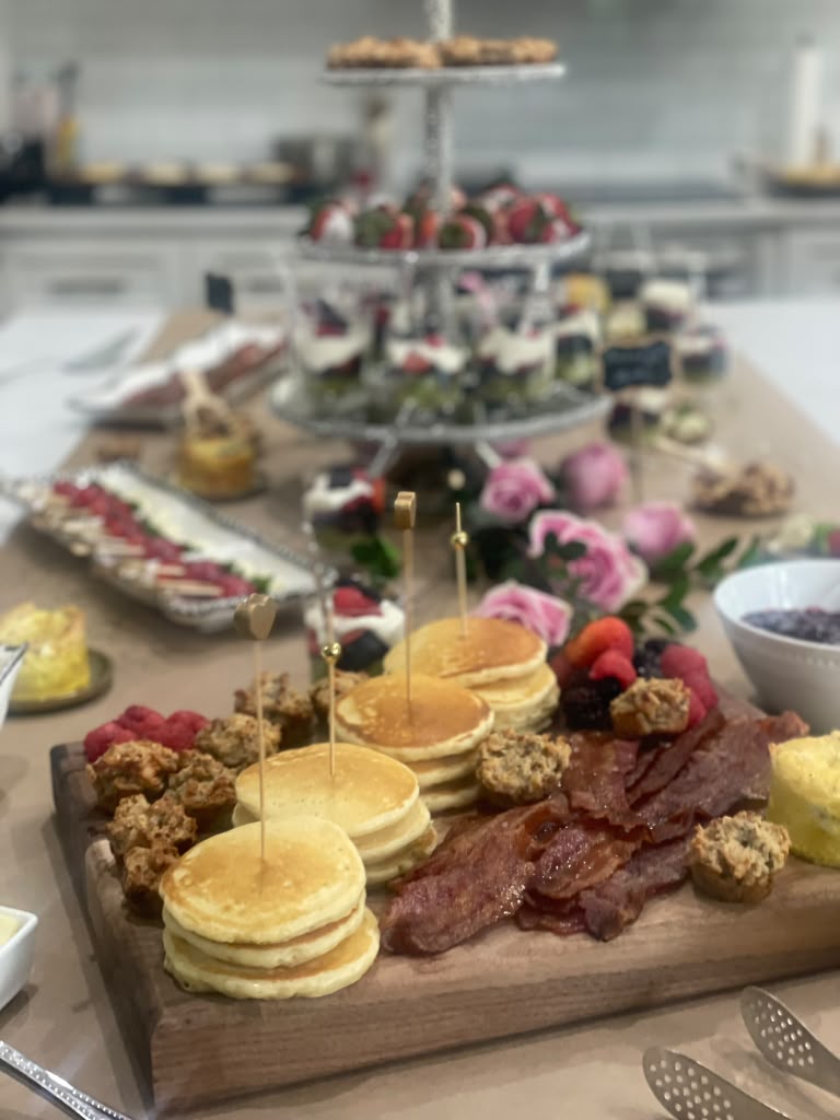 Brunch grazing board with mini pancakes, bacon, berries and muffins